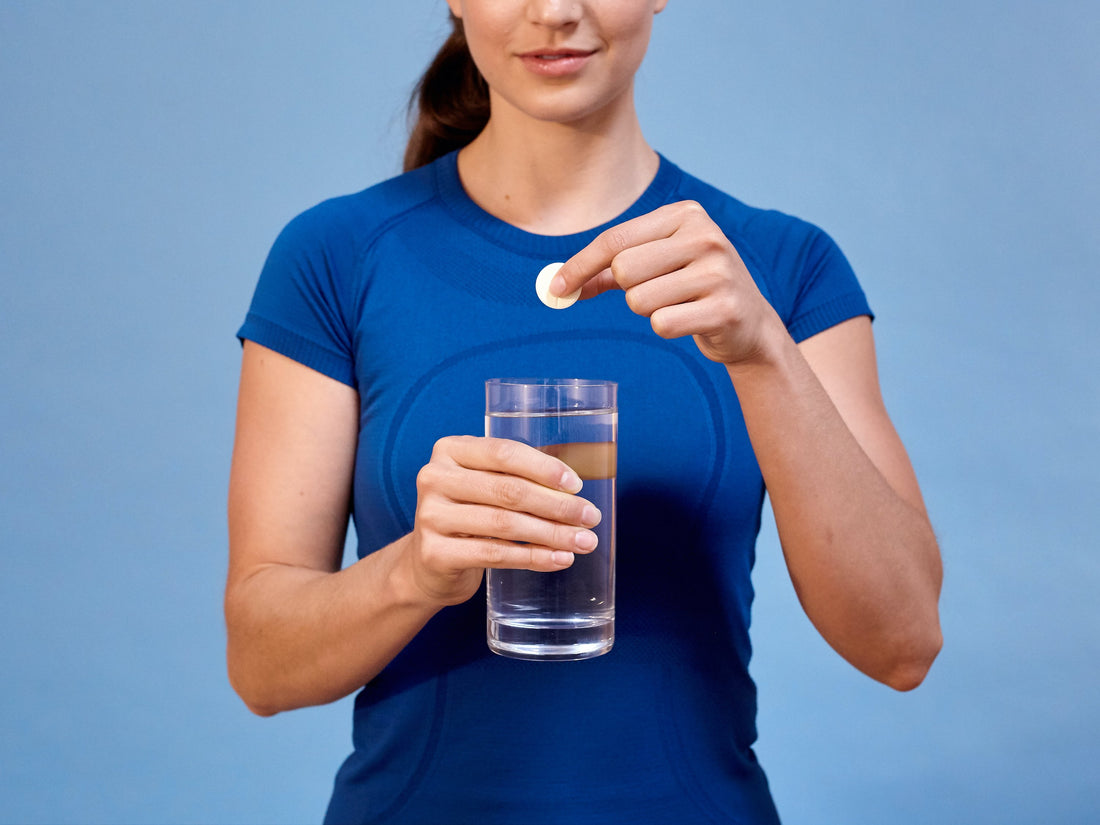 person dropping a nuun tablet into a glass of water