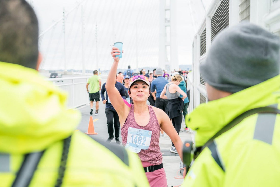 runner holding up a hydration cup during a race