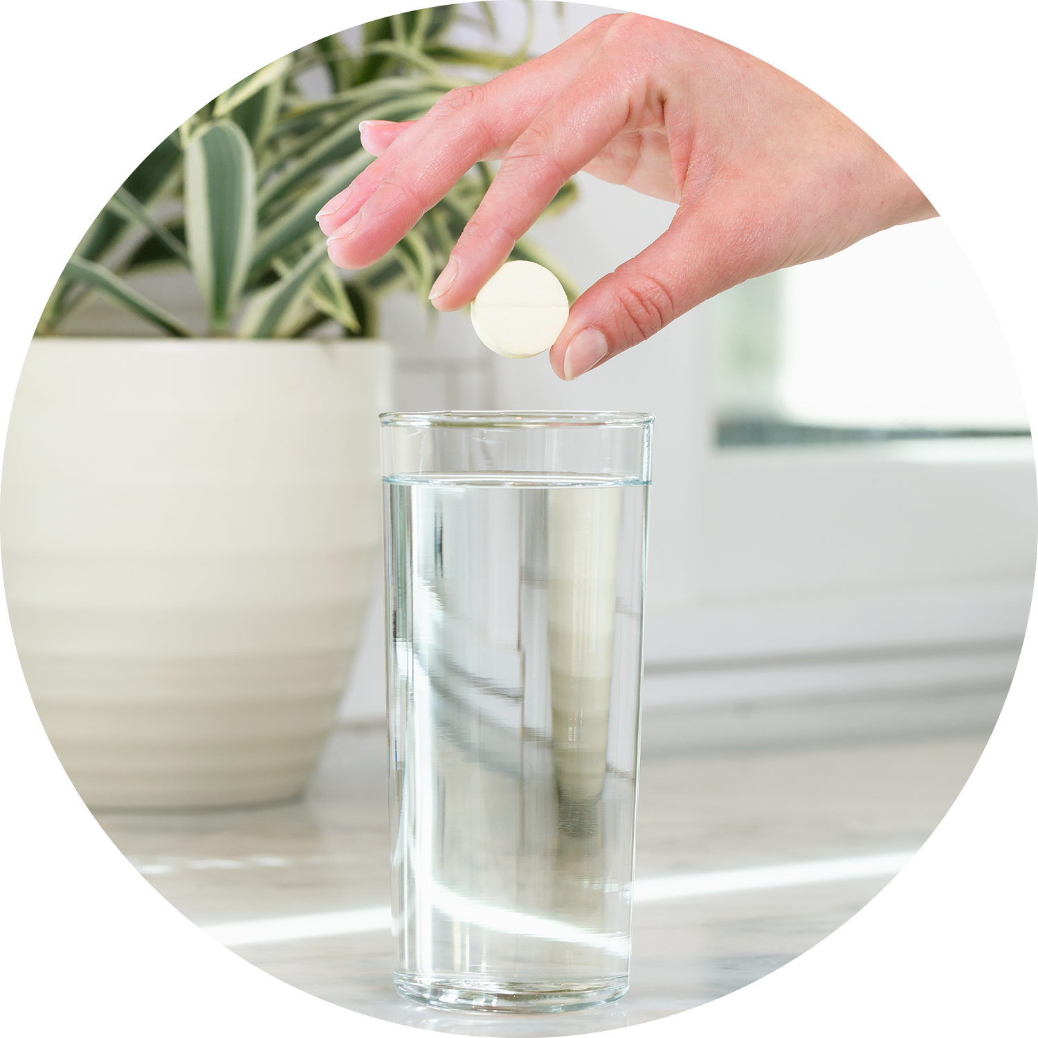 Hand dropping a tablet into a glass of water